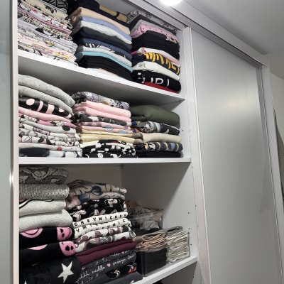 בגדים מקופלים בארון לבן עם מדפים