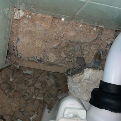 צינור פלסטיק לבן עם חיבור שחור בקיר שבור