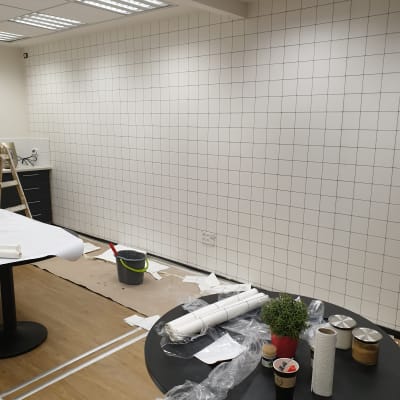 קיר עם טפט מרובע, שולחנות עם כלים וחומרים