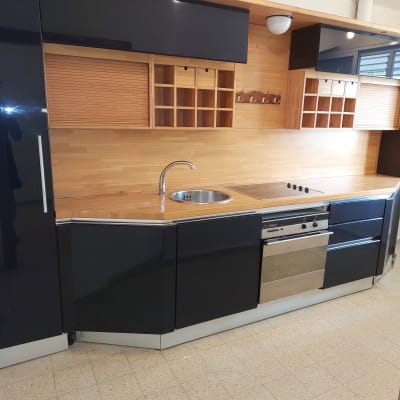 מטבח עם ארונות שחורים ומשטח עץ, כיור וברז