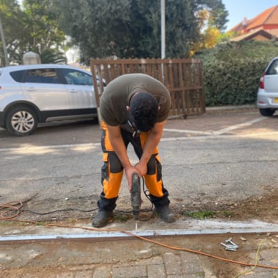 אדם קודח מסגרת מתכת על המדרכה