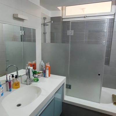 מקלחון זכוכית עם דלתות חלביות בחדר אמבטיה