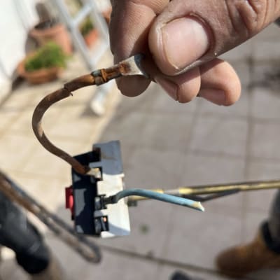 חוטים מחוברים למתג חשמלי ביד אדם