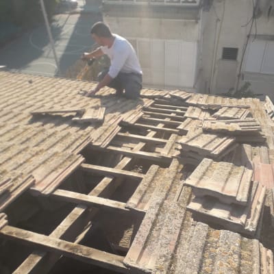 אדם עובד על גג רעפים עם כלי עבודה