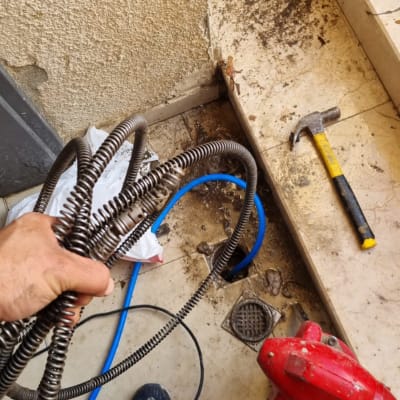 יד מחזיקה קפיץ אינסטלציה ליד פתח ניקוז