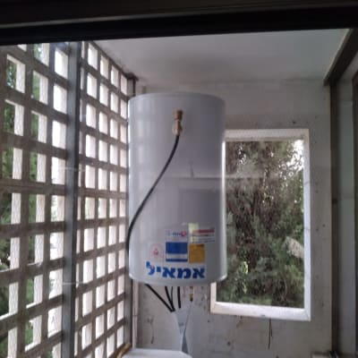 דוד שמש לבן עם צינור על קיר מרפסת