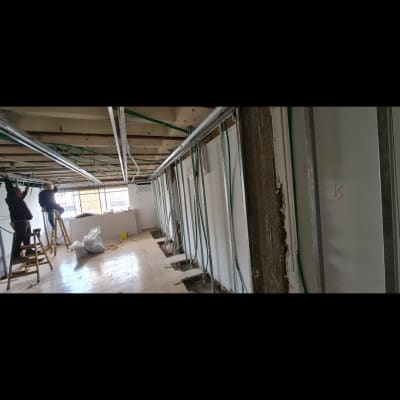 עובדים על סולמות מתקינים תקרת גבס עם מסגרות מתכת