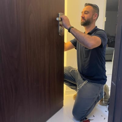 אדם מתקין ידית על דלת עץ חומה