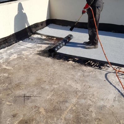 אדם מבצע איטום גג עם יריעות ביטומניות