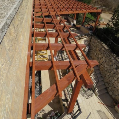 פרגולה מעץ חום בחצר עם שביל אבן