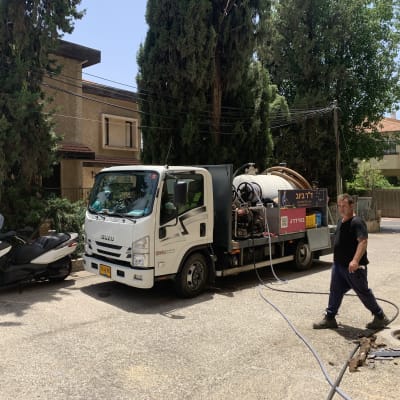 משאית ואקום עם צינורות ליד פתח ביוב פתוח