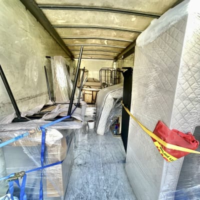 משאית הובלה עם מזרנים וארגזים קשורים ברצועות