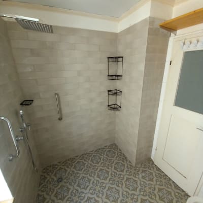 מקלחת עם אריחים חדשים, מדפים ומוט אחיזה