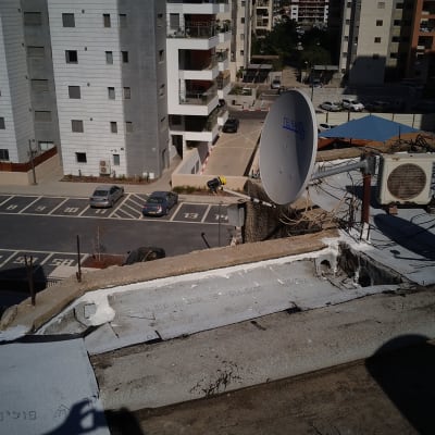 איטום גג עם חומר לבן ליד צלחת לוויין