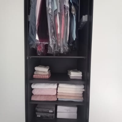 בגדים תלויים ומגבות מקופלות בארון שחור