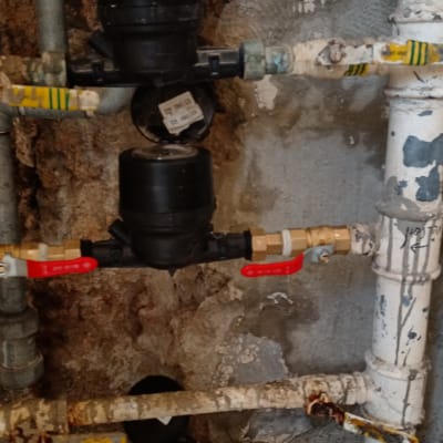 צינורות מים עם ברזים אדומים ושעון מדידה