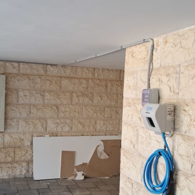 עמדת טעינה לרכב חשמלי עם כבל כחול על קיר אבן