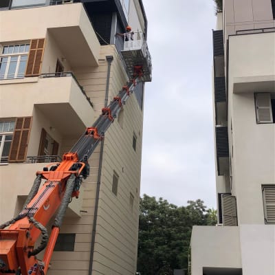 אדם מנקה חלון עם מנוף על בניין גבוה