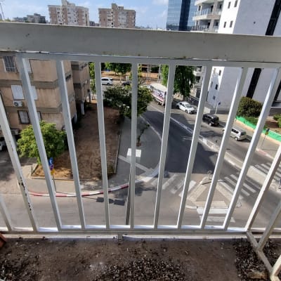 מעקה מתכת לבן עם סורגים אנכיים במרפסת