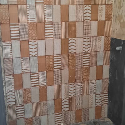 קיר עם אריחים מעוצבים ודלי צבע על הרצפה