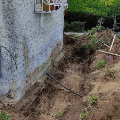 חפירה ליד קיר בניין עם צינור חשוף
