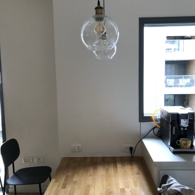 מנורת תלייה עם נורה חשופה מעל שולחן עץ