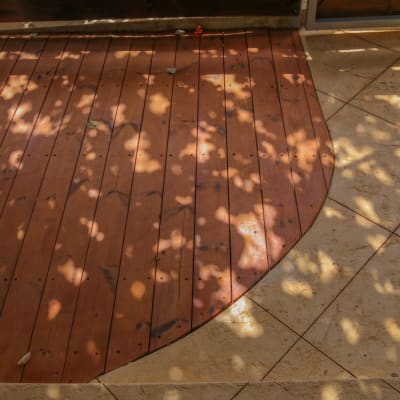 דק עץ עם צללים על רצפת אבן בגינה