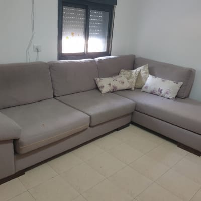 ספה אפורה עם כריות דקורטיביות על רצפה בהירה