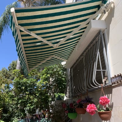 סוכך פסים ירוק לבן מותקן על קיר חיצוני
