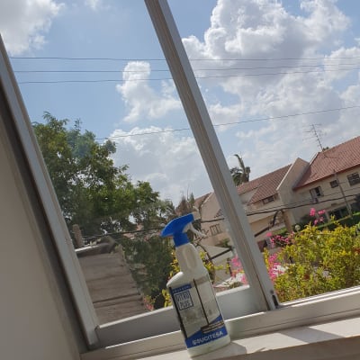 בקבוק תרסיס ניקוי על אדן חלון פתוח