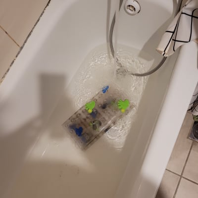 מכשיר פלסטיק עם כפתורים ירוקים וכחולים באמבטיה מלאה מים