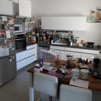 מטבח עם כלים על השיש, מכונת קפה, צנצנות ותבלינים.