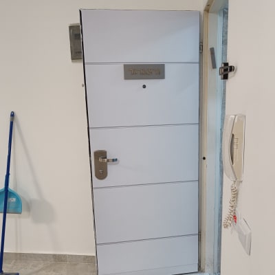 דלת לבנה עם ידית מתכת, שלט שם על הדלת