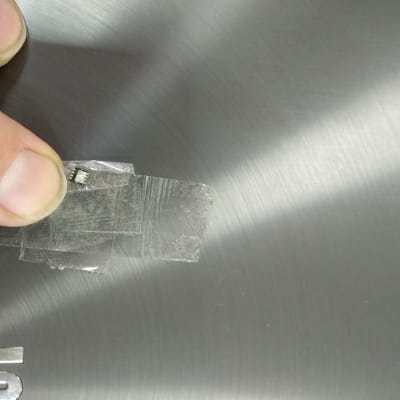 אצבע מחזיקה שבב קטן על רקע מתכת