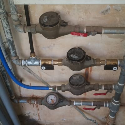 מד מים וצינורות מתכת עם ברזים אדומים