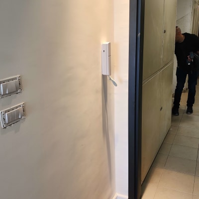 אינטרקום לבן מותקן על קיר לבן