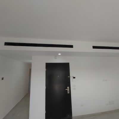 קיר גבס עם פתחי אוורור מעל דלת שחורה