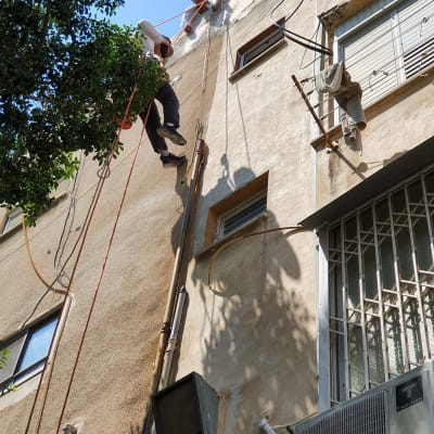 שני עובדים תלויים על חבלים בצד בניין