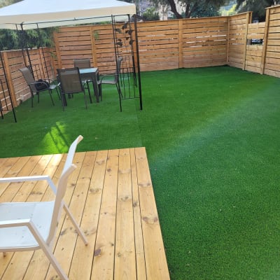 דשא סינתטי עם פרגולה וכיסאות גינה