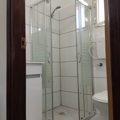 מקלחון זכוכית חדש עם אריחים לבנים ושירותים
