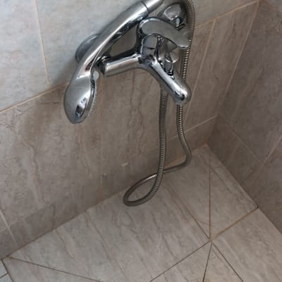 ברז מקלחת עם צינור מתכת ורצפת קרמיקה