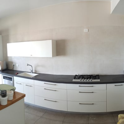 מטבח עם ארונות לבנים ומשטח עבודה כהה