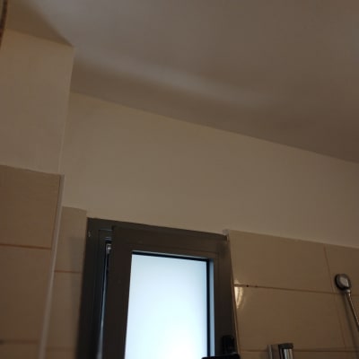 קיר צבוע בלבן ליד חלון עם מסגרת מתכת