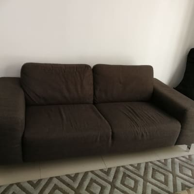 ספה חומה עם רגלי מתכת על שטיח גיאומטרי