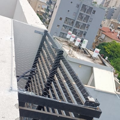 רשת מתכת מותקנת על מעקה למניעת יונים
