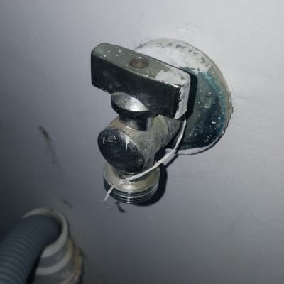 ברז מים מתכת מחובר לקיר עם צינור פלסטיק