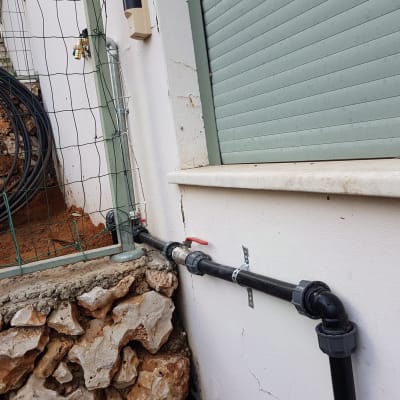 צינור מים שחור עם ברז על קיר חיצוני