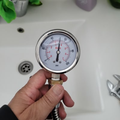 מד לחץ אוויר מוחזק ביד מעל כיור