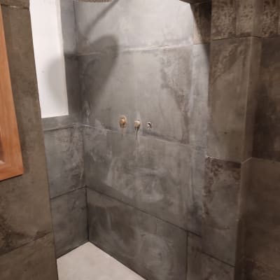 מקלחת עם אריחים אפורים וראש מקלחת מותקן