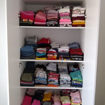 בגדים מקופלים בארון לבן עם מדפים פתוחים